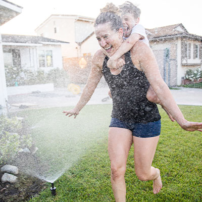 Family running through sprinklers